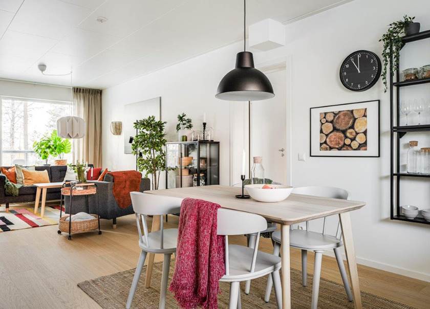 Matbord med fyra stolar i kök som är öppet mot vardagsrum i BoKlok lägenhet.