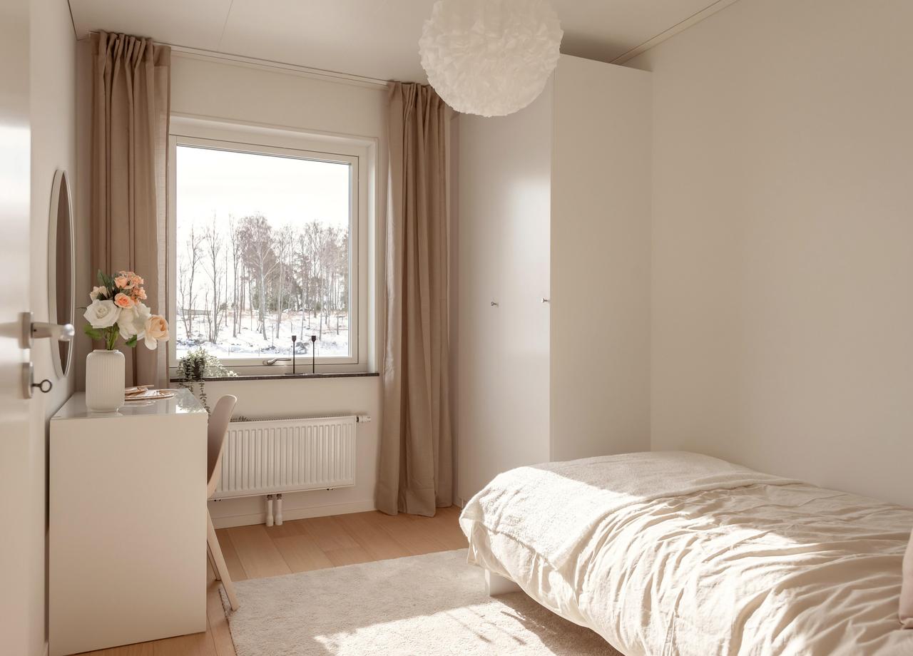Foto på ett sovrum med fönster, enkelsäng och skrivbord