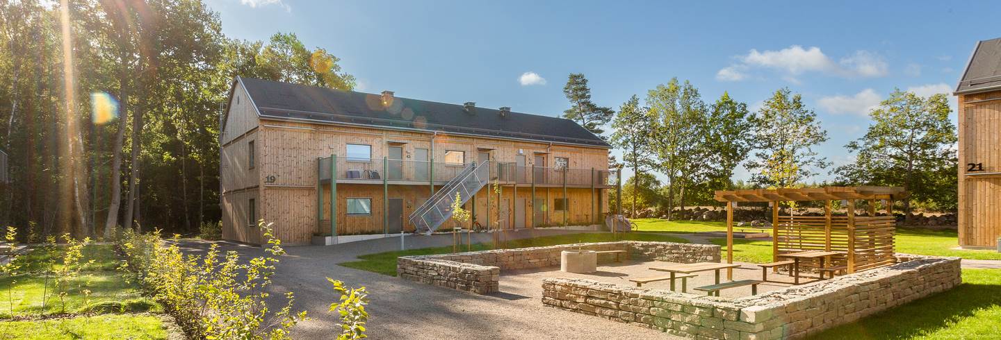 Lägenhetshus med innergård med pergola inramad av ölandssten i BoKlok Gläntan i Färjestaden på Öland Lägenhetshus med innergård med pergola inramad av ölandssten i BoKlok Gläntan i Färjestaden på Öland