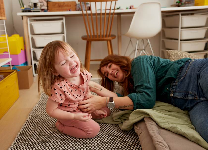 Flicka och kvinna leker och skrattar på golvet