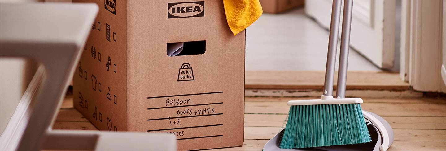 En packad flyttkartong med IKEA logo på sidan och ett sopskyffelset som står jämte