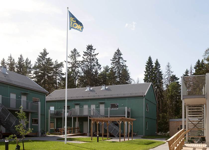 Gröna lägenhetshus med flagga på gemensam innergård i BoKlok Flinta i Enköping.