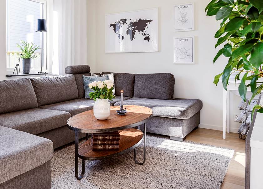 Soffhörn vid fönster i ett BoKlok radhus med grå soffa och matta samt brunt soffbord. Soffhörn vid fönster i ett BoKlok radhus med grå soffa och matta samt brunt soffbord.