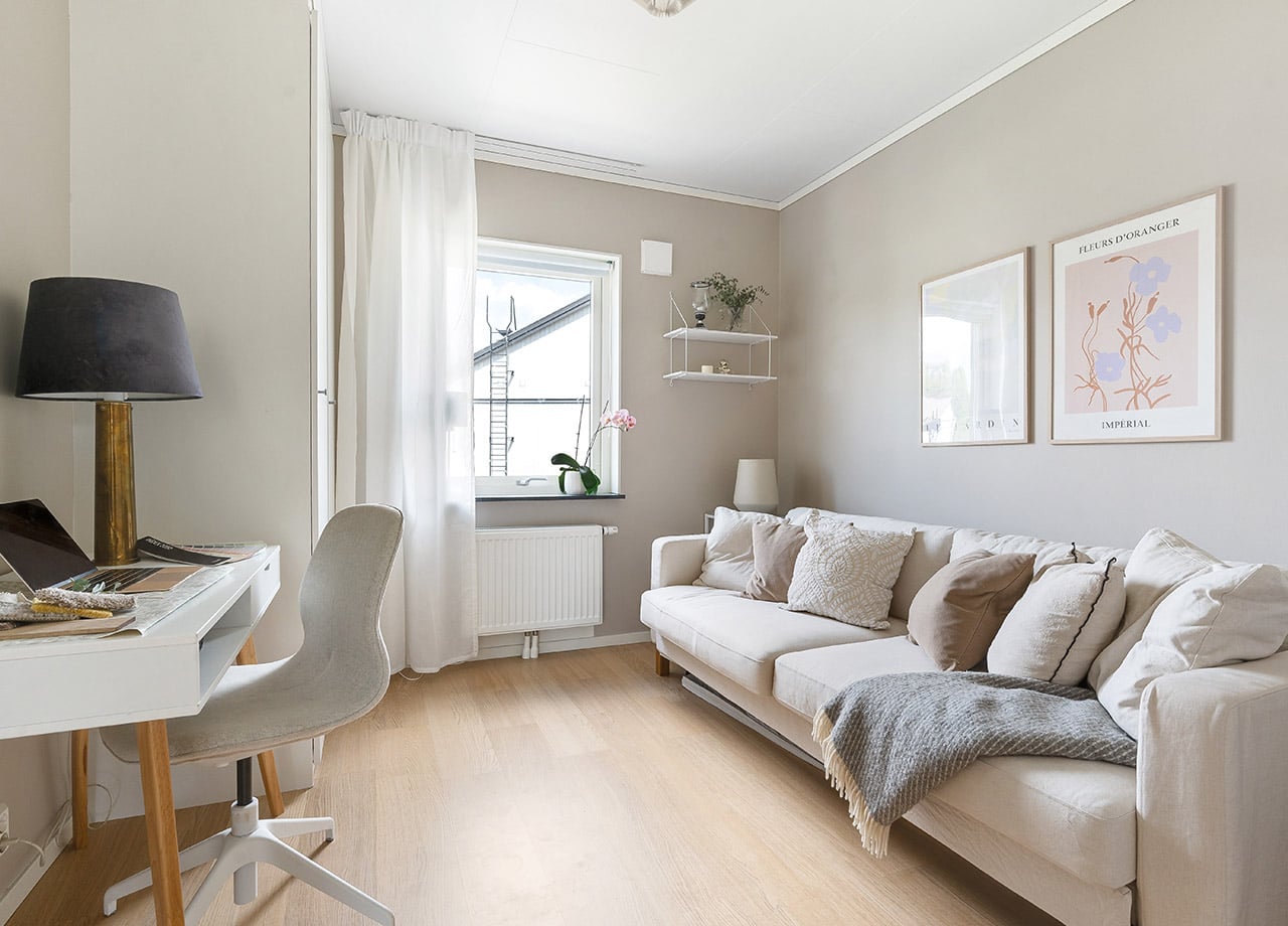Kontor med soffa i ljusa grå och beige kulörer i ett BoKlok radhus.