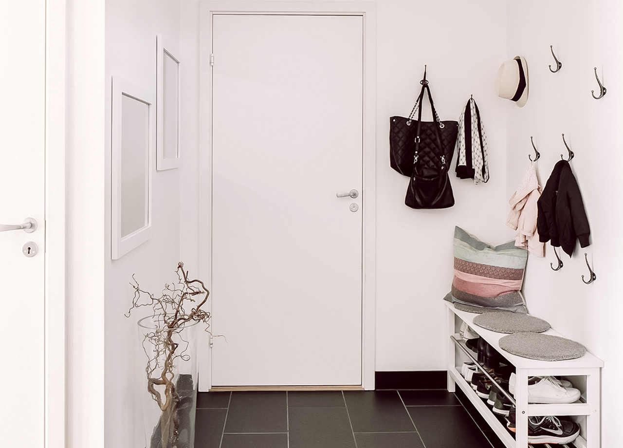 Hall med vita väggar och grå klinker