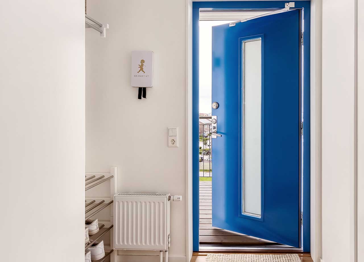 Hall med blå ytterdörr som står på glänt. 