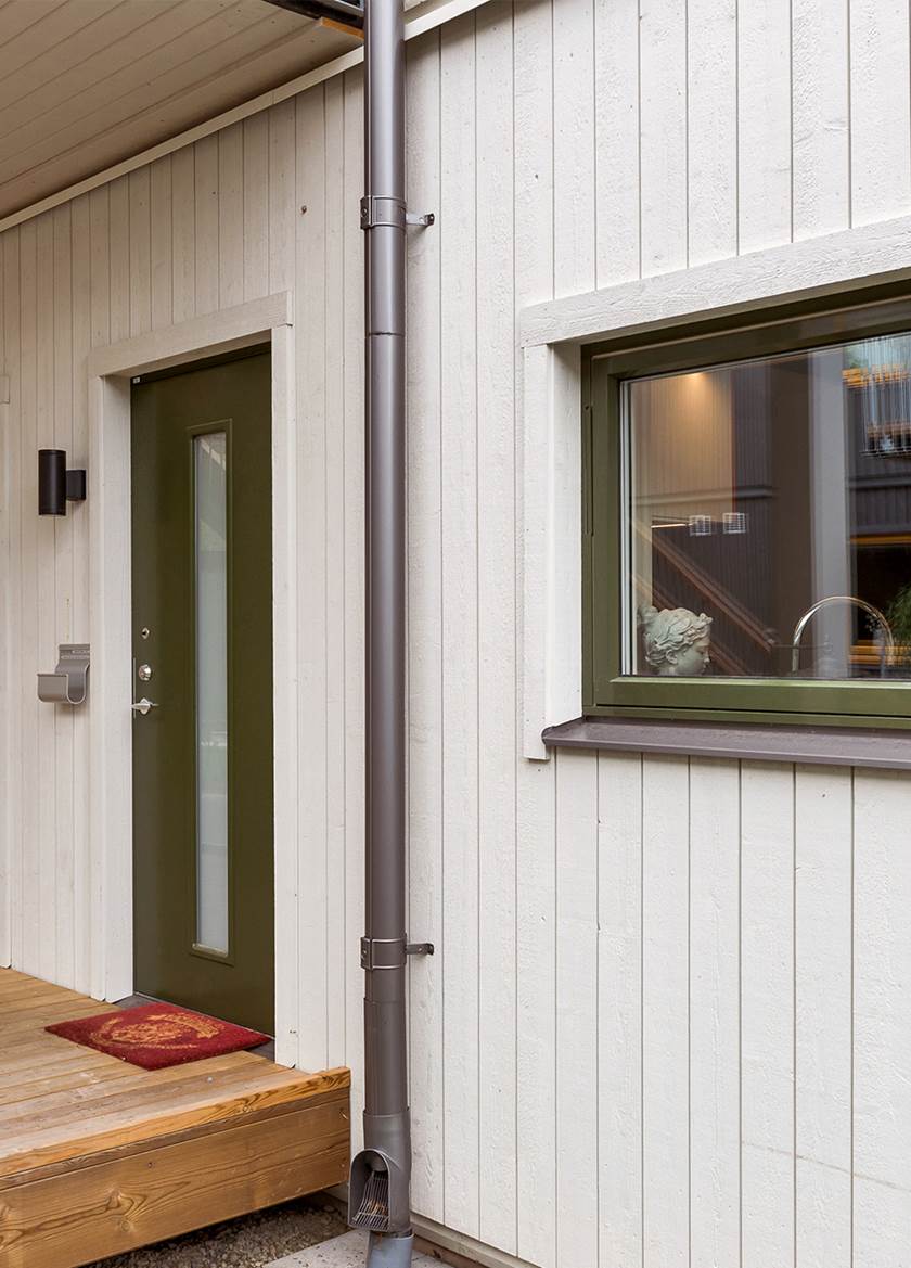 Grön dörr i vitt BoKlok flerfamiljshus, på bottenplan Grön dörr i vitt BoKlok flerfamiljshus, på bottenplan