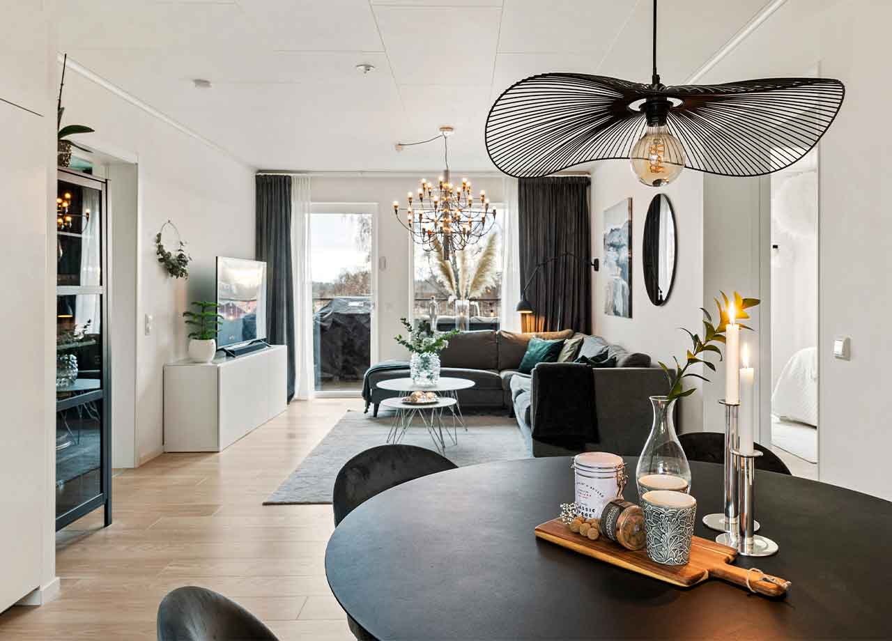 Köksbord i förgrunden med vardagsrum och öppet till balkong