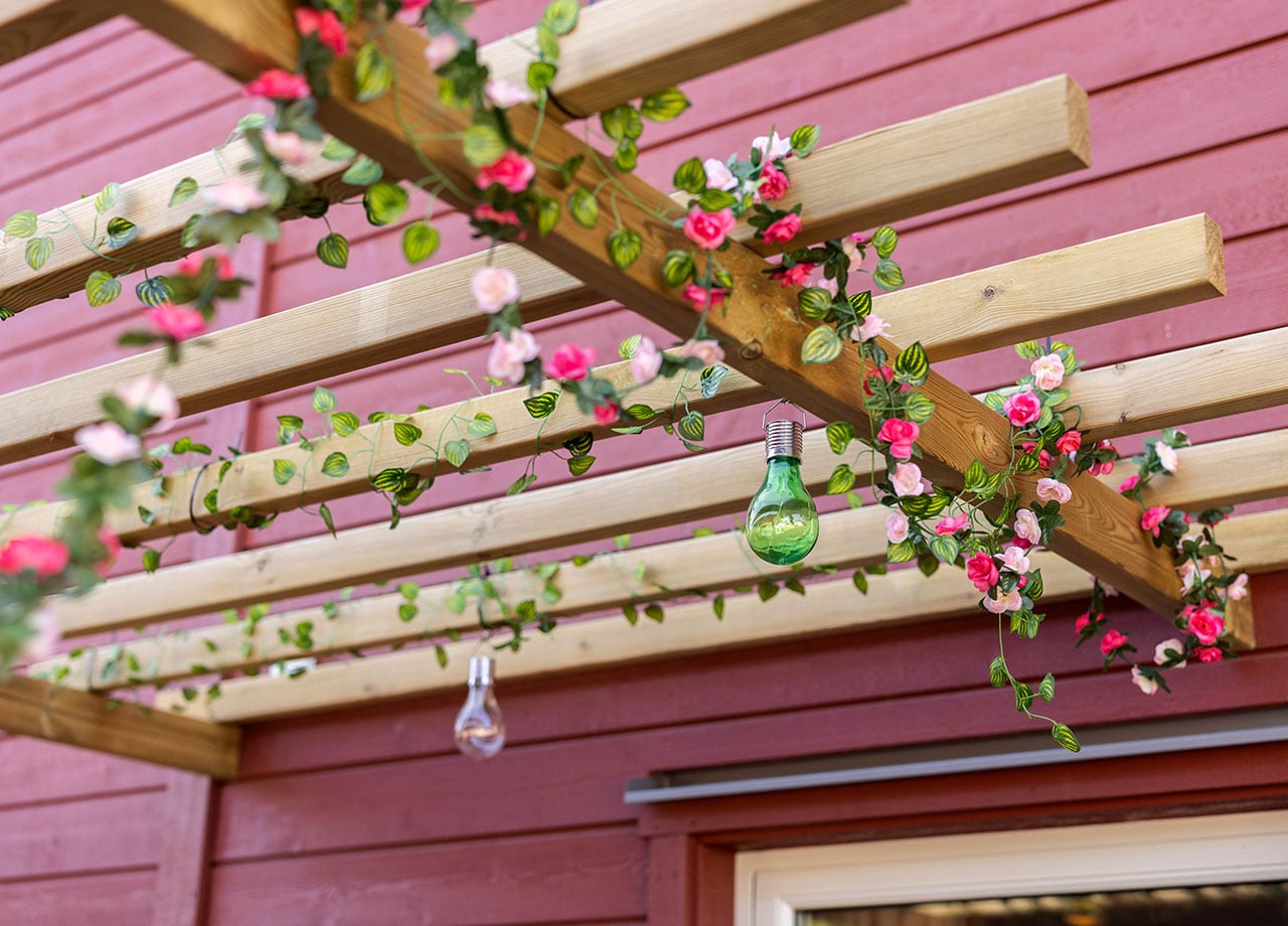 Blommor i pergola över altan