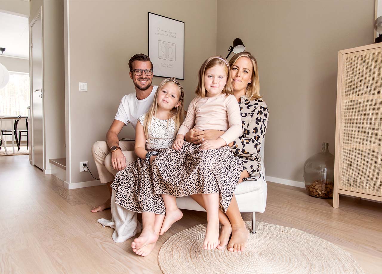 Familj om fyra sitter på divan i vardagsrum