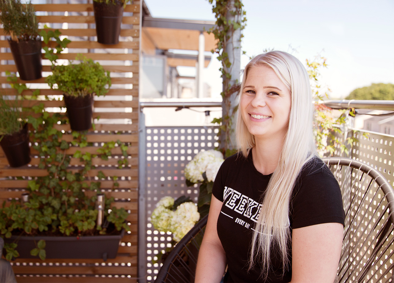 Emma Malmborg leende sittande på sin balkong