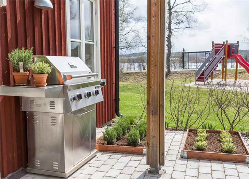 Grillplats på sten med grill i rostfritt. Odlingslådor på marken bredvid. Grillplats på sten med grill i rostfritt. Odlingslådor på marken bredvid.