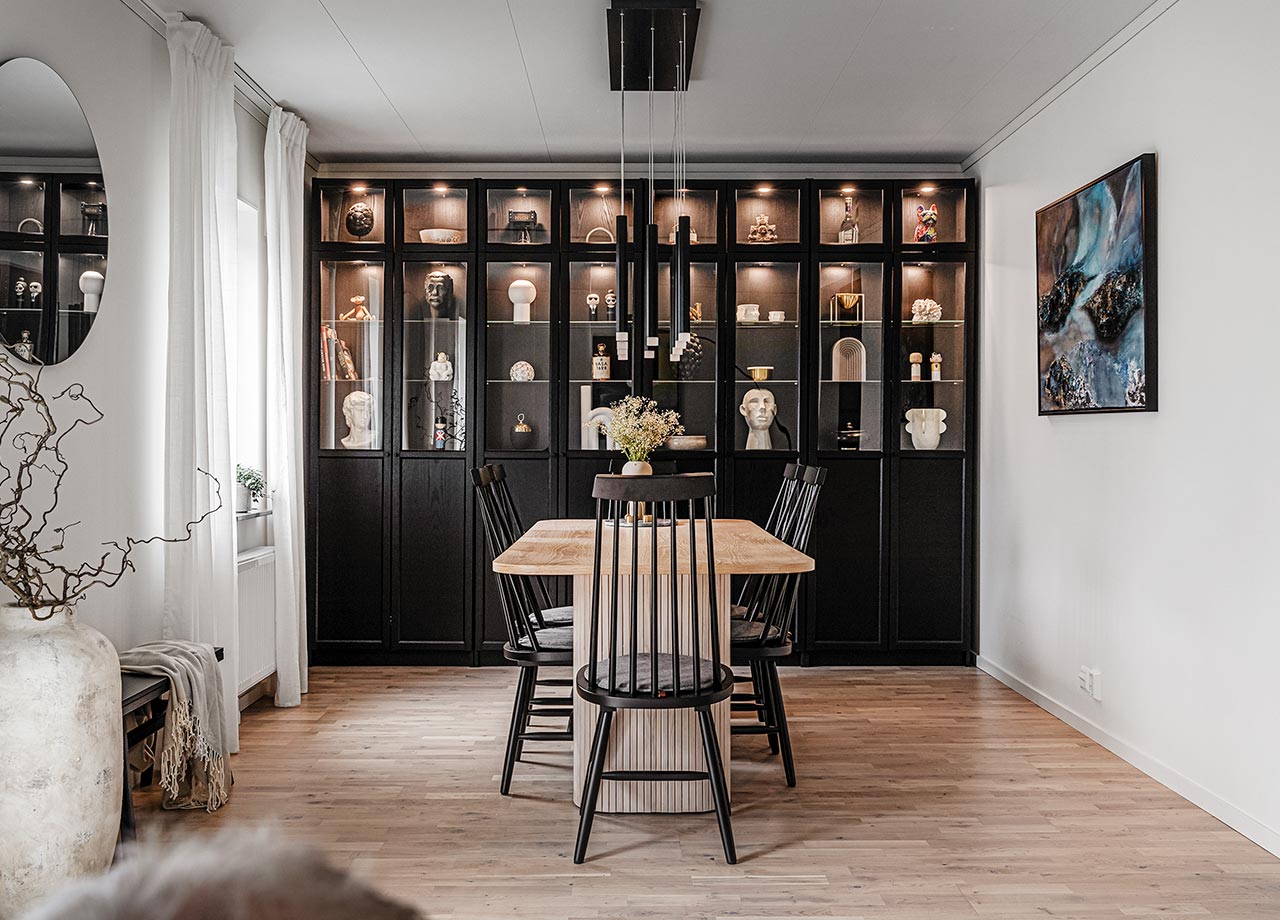 Svart vitrinskåp med belysning och matbord framför