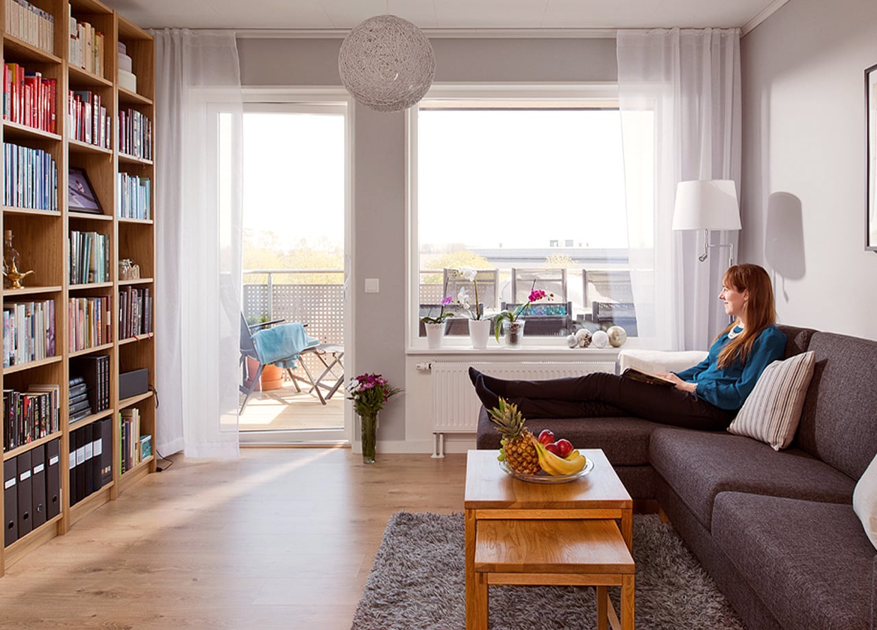 Kvinna sitter i soffa och kollar ut mot balkong