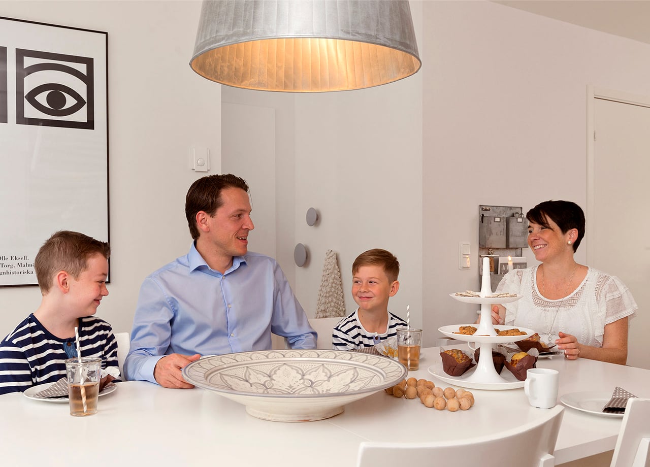 Familj på fyra sitter och fikar vi matbord