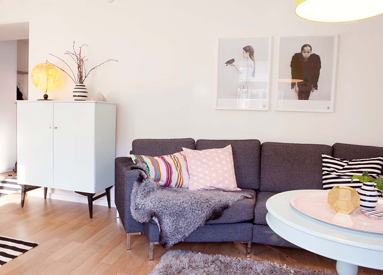 Vardagsrum med grå soffa och rosa kuddar
