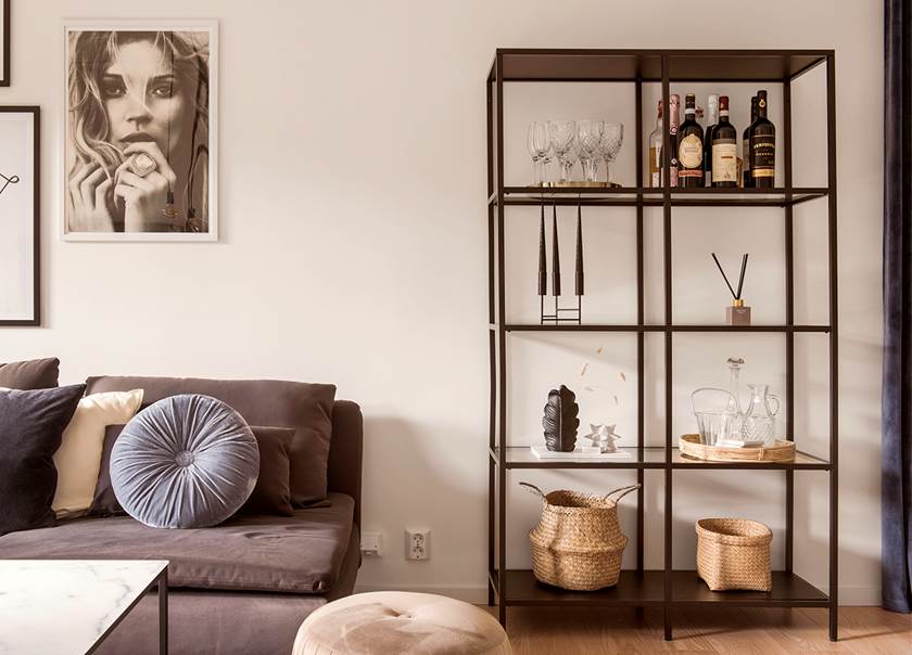 Förvaringshylla Vittsjö från IKEA med svart metallram och hyllplan i klarglas, bredvid grå soffa. Förvaringshylla Vittsjö från IKEA med svart metallram och hyllplan i klarglas, bredvid grå soffa.