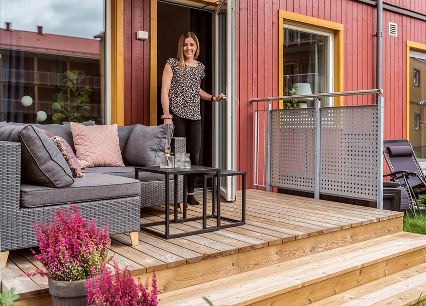 Trädäck med grå soffgrupp och kvinna i mellanblont hår i terassdörren. Trädäck med grå soffgrupp och kvinna i mellanblont hår i terassdörren.