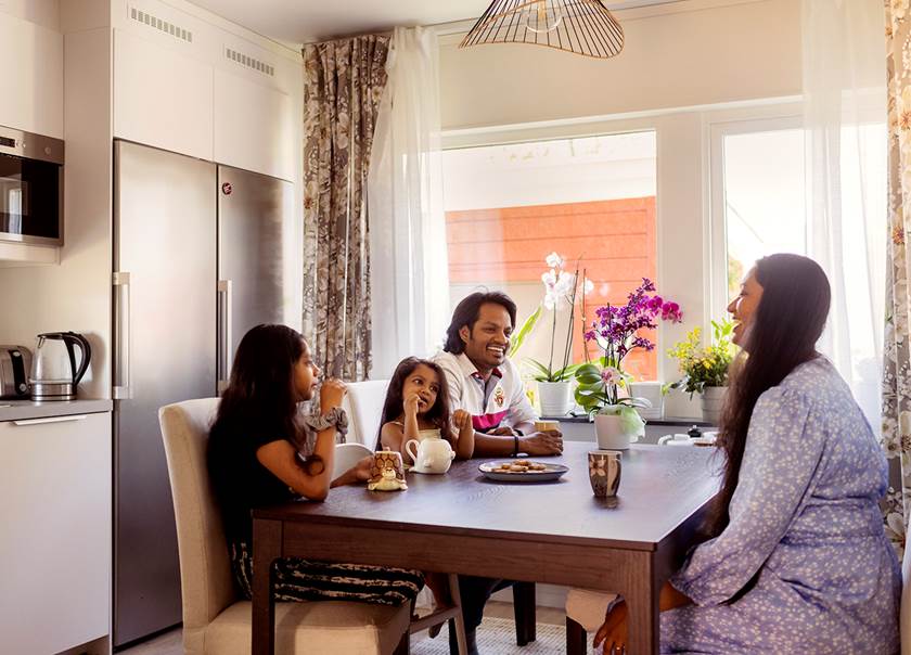 Familj fikar vid brunt bord i köket i ett Boklok radhus