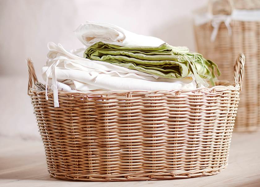 tvättkorg i pil med vikt tvätt i vitt och grönt