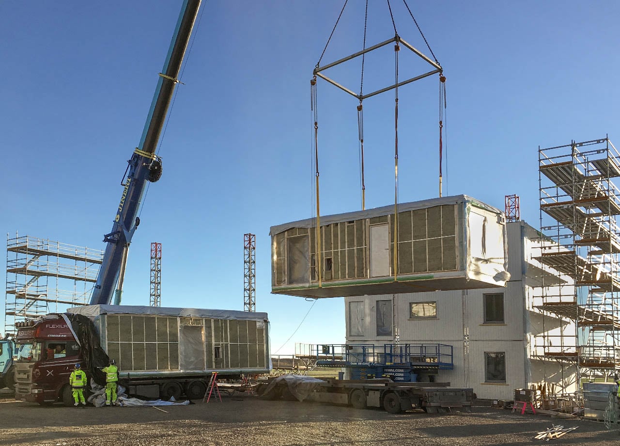 Lägenhetsmoduler lyfts på plats med hjälp av en kranbil
