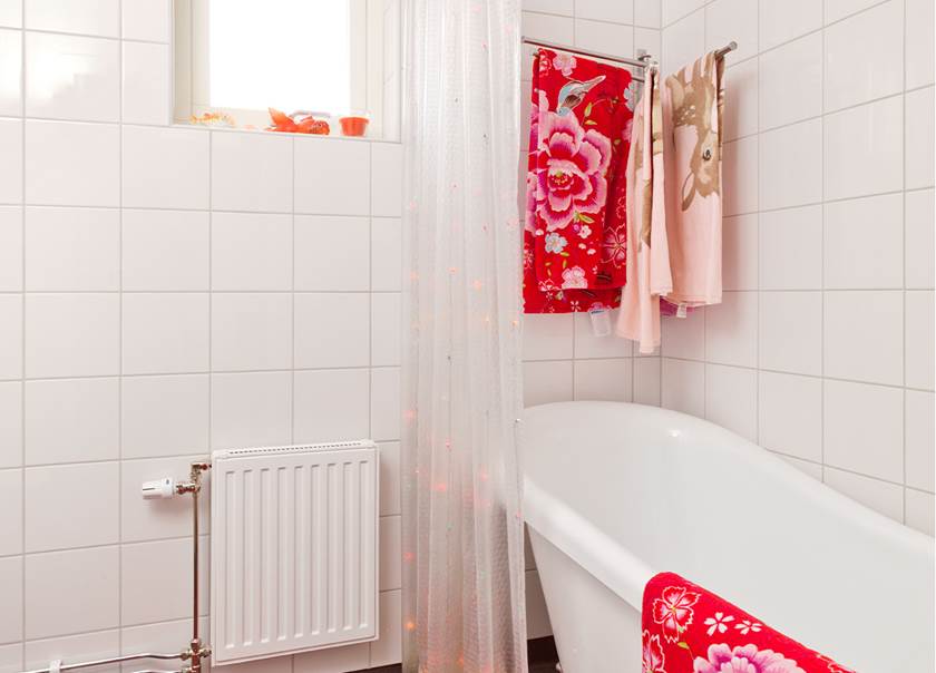 Helkaklade badrummet med badkar med mönstrade handdukar i familjen Beijers Boklok radhus