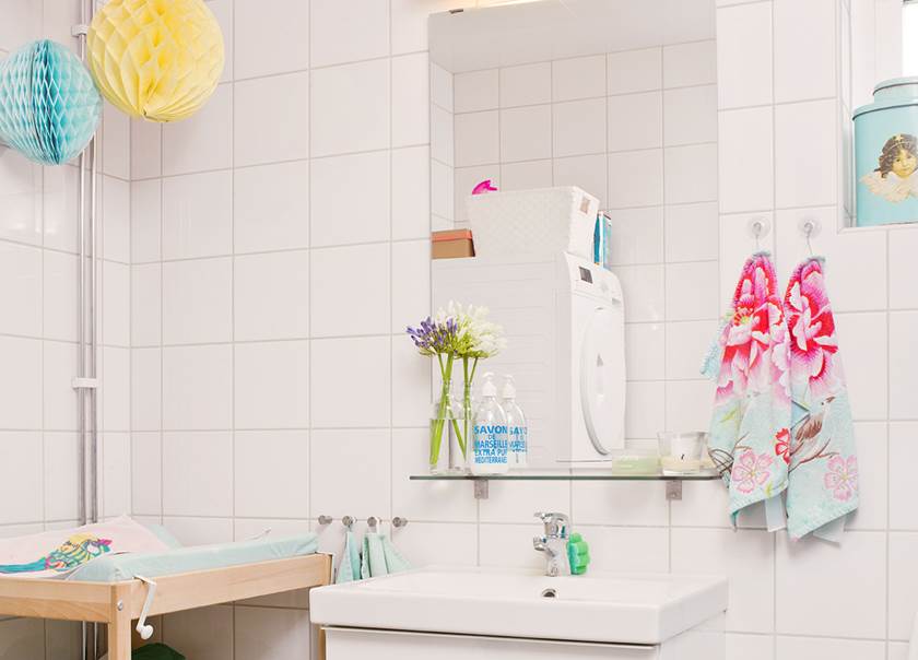 Helkaklade badrummet med spegel över handfat och tvättpelare och färgglada detaljer