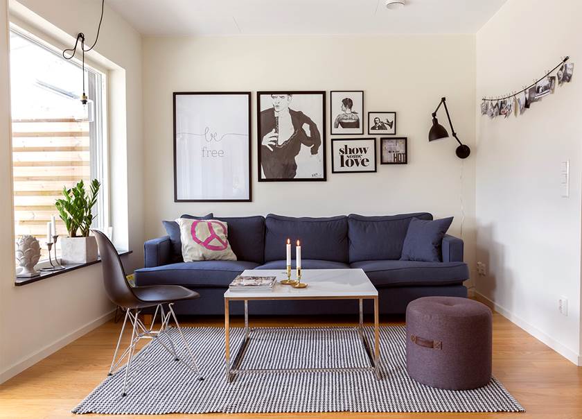 Mörkblå soffa med tavlor hängande på väggen i vardagsrum i Boklok radhus hemma hos familjen Hellström-Kjellström 