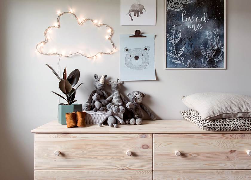 Gosedjur kuddar växt på björkbyrå med bilder och molnlampa uppsatta på väggen bakom hemma hos familjen  Johansson-Jonsson