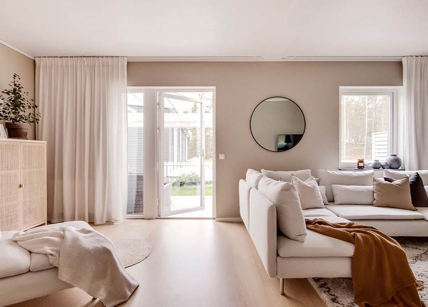 Vardagsrum med vit soffa brun filt bredvid terassdörr i BoKlok radhus 