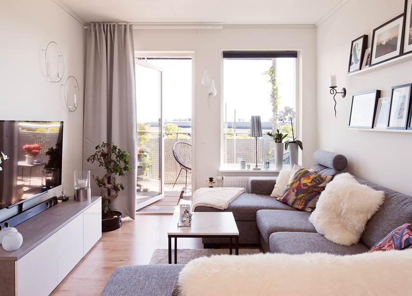 Vardagsrum med plats för soffa, soffbord och tv i BoKlok lägenhet med öppen dörr ut till balkongen hemma hos Malmborg