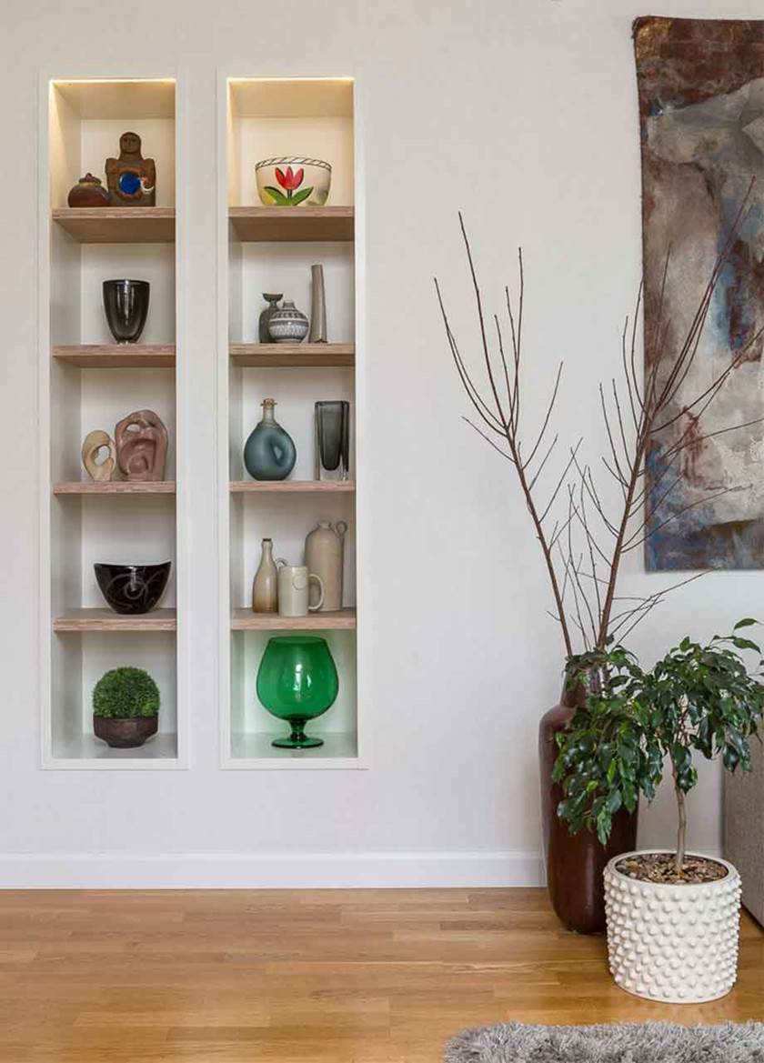Infälld bokhylla med vaser, keramikfigurer och skålar, infälld i vägg i vardagsrum