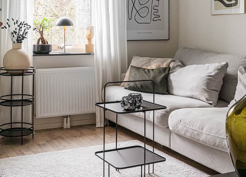 Ljusgrå soffa och svart litet soffbord på ljusgrå matta.