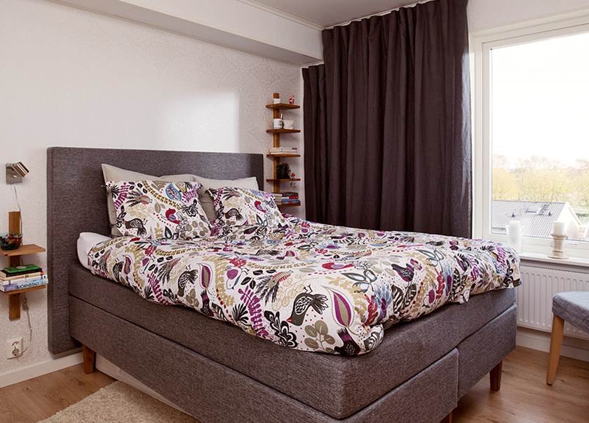 Säng med mönstrade påslakan och grå sänggavel i sovrum hemma hos McKnight