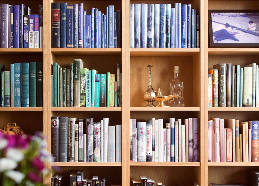 Välfylld bokhylla med böcker koordinerade i färger som blå, grönt och rosa hemma hos Micknight.