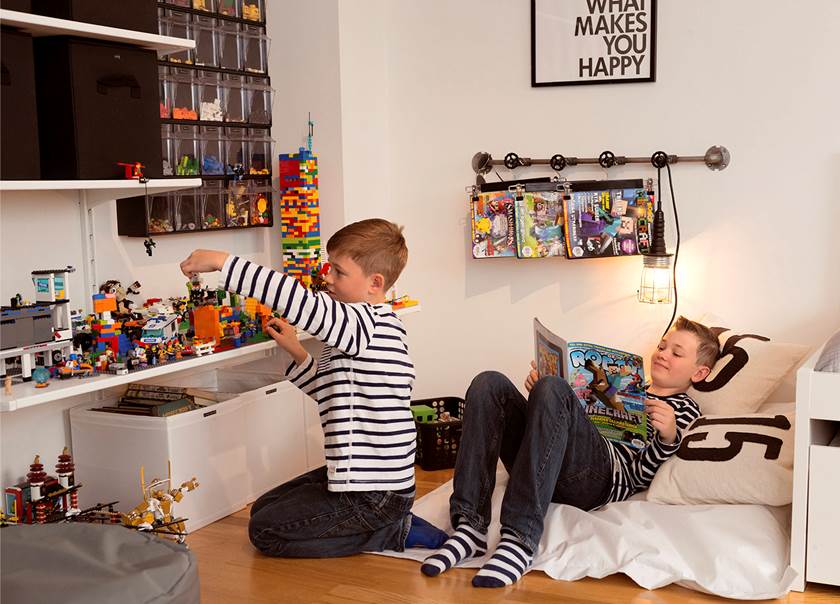 Två pojkar leker i rum fullt med leksaker