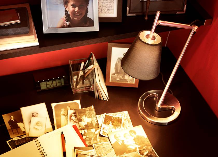 Skrivbordslampa lyser över skrivbord med gamla svartvita foton.