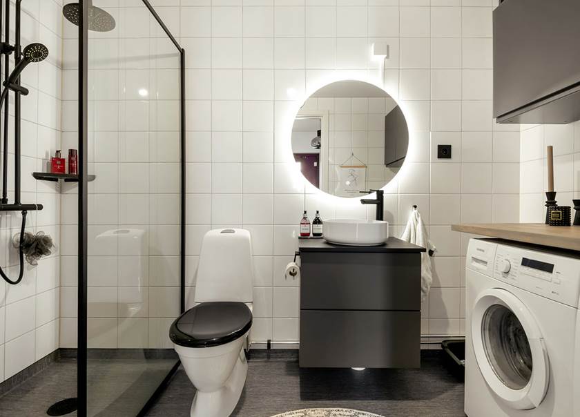 vitt badrum med svarta detaljer och spegel med ljus