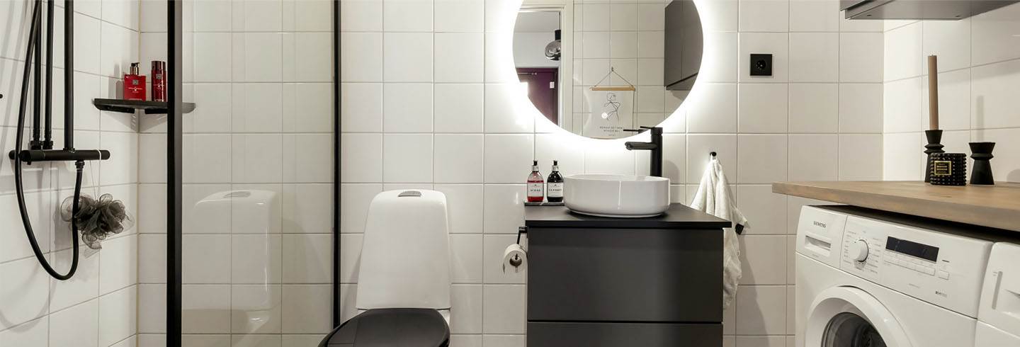 duschkabin och gråa möbler i vitkaklat badrum