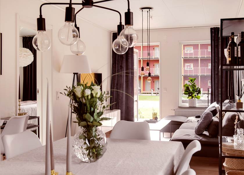 matbord med vit duk och vita rosor med utsikt mot vardagsrum och träterass och