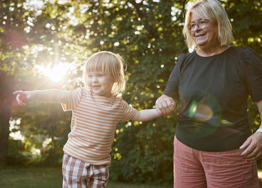 Äldre kvinna håller flicka som pekar mot något i handen.