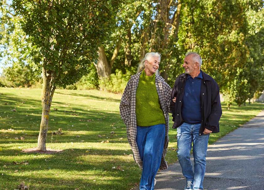 Äldre par på promenad håller armkrok.