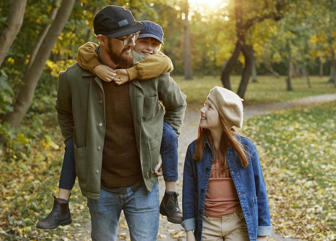 Foto på pappa och två barn som promenerar i skogen