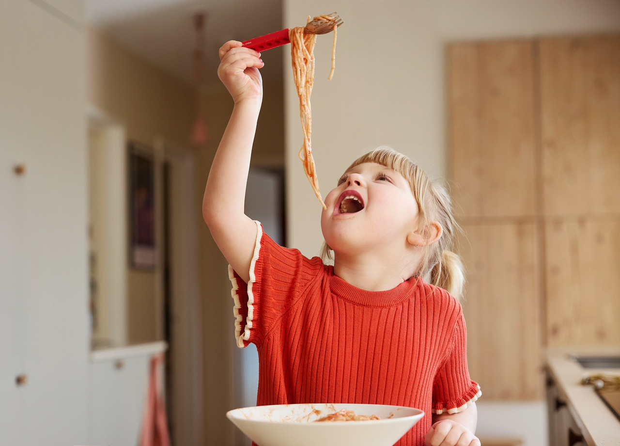 Flicka äter spagetti med ätpinnar.