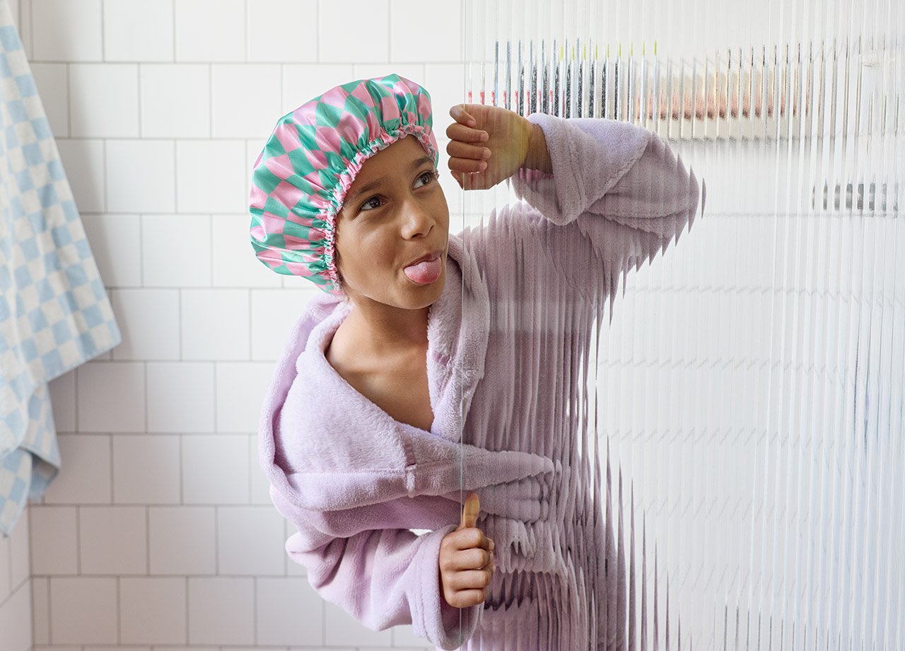 Flicka i dusch med badmössa som räcker ut tungan.