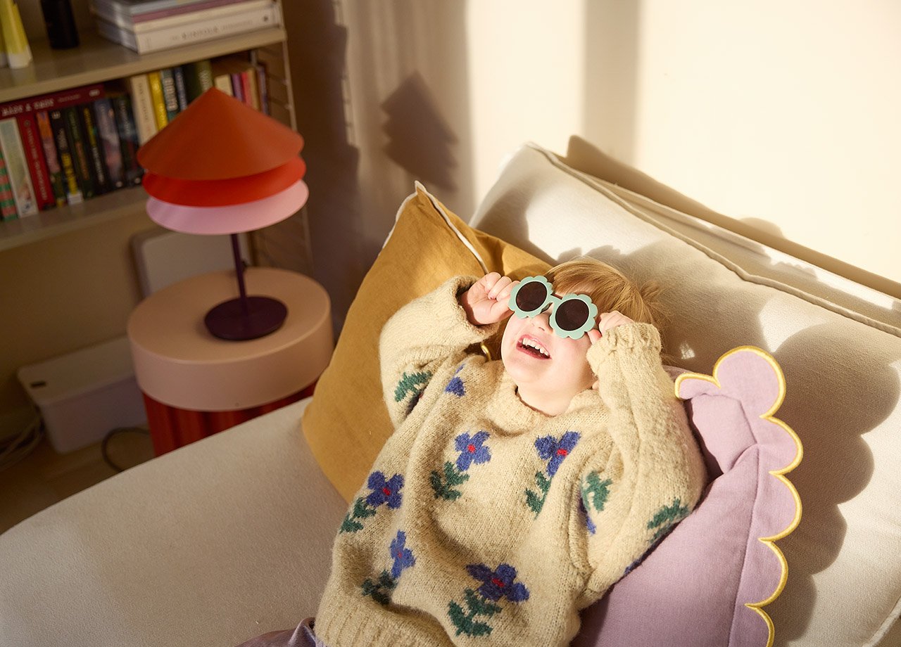 Flicka med solglasögon sitter i fåtölj.