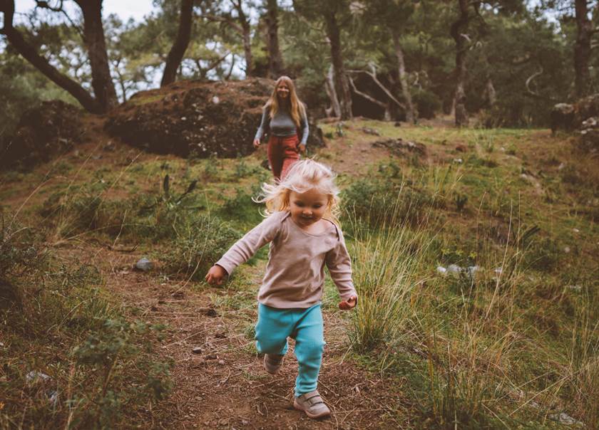 Flicka springer  i skogen med sin mamma hack i häl.