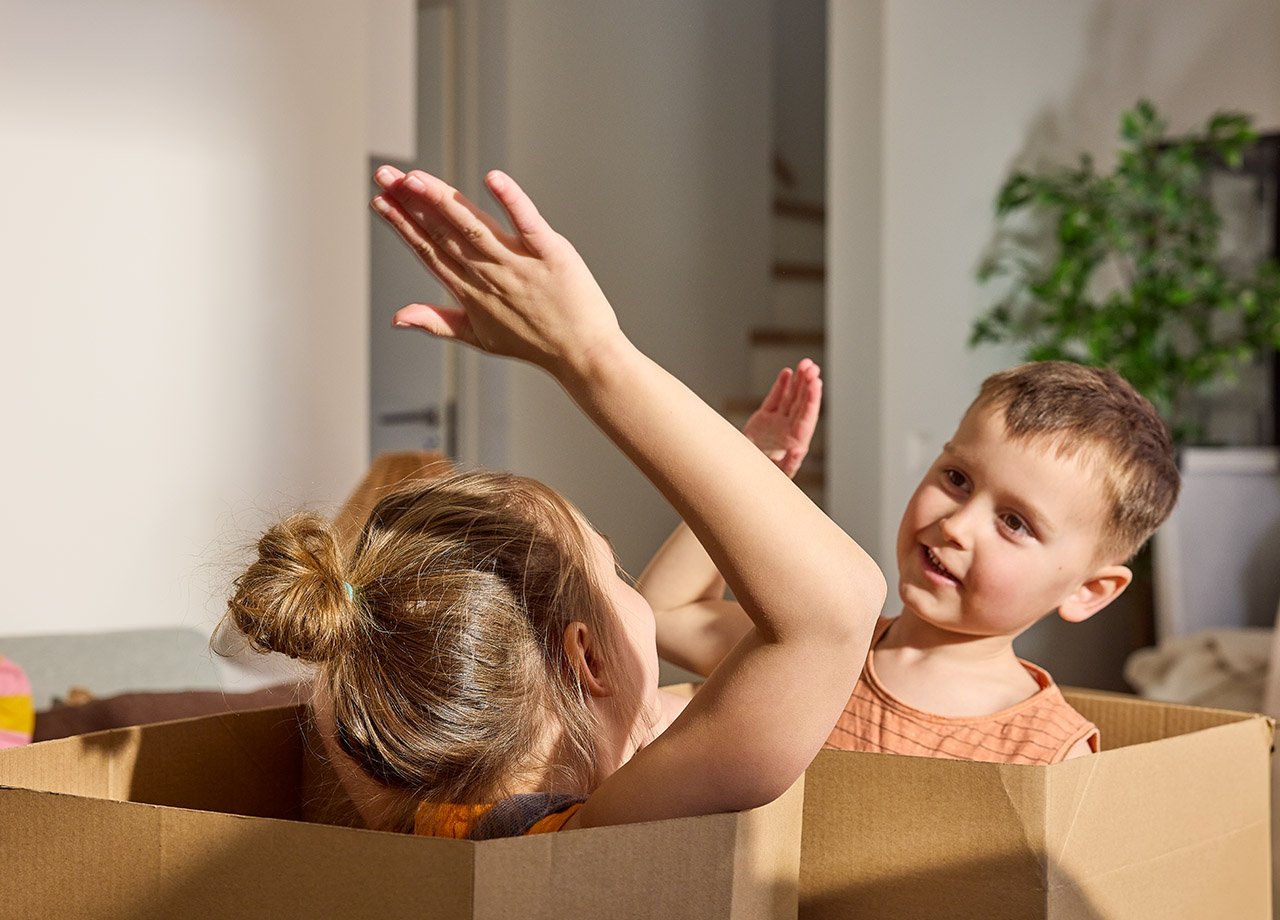 Pojke och flicka leker sittande i flyttkartonger.