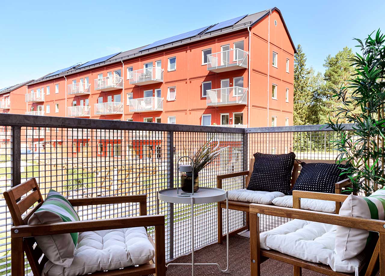 Möblerad balkong med grönskande träd och gräs i bakgrunden.