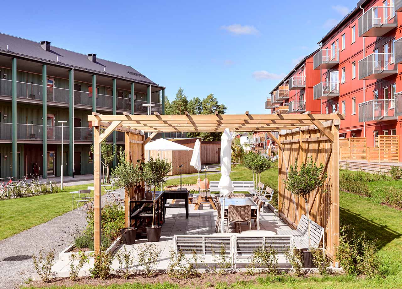 Foto av innergården med gillm bänkar och bord i BoKlok Duetten.